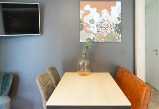 Eettafel met moderne kunst en televisie in Thor cottage bij Hoge Kempen in België.