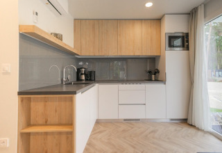 Cocina moderna en Thor Cottage, Hoge Kempen, Bélgica, con armarios de madera y electrodomésticos integrados.