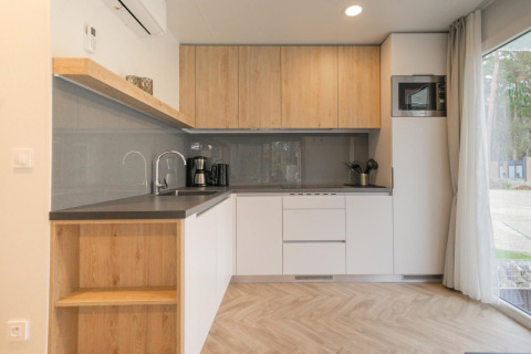 Modern kitchen corner in Thor Cottage at Hoge Kempen, Belgium, featuring wooden cabinets and appliances.