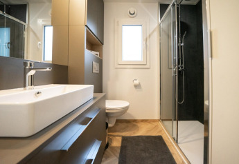 Baño moderno en la cabaña Thor en Hoge Kempen, Bélgica, con ducha, lavabo, inodoro y espejo grande.