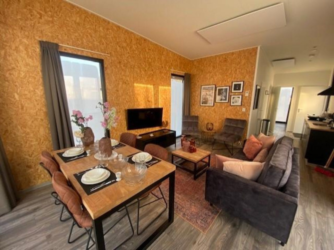 Cozy living and dining area with wood panel walls at Just Nature Light, IJssel Islands, Netherlands.