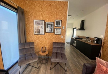 Woonkamer met moderne stoelen, wanddecoratie en open keuken bij Just Nature Light op de IJssel Islands.