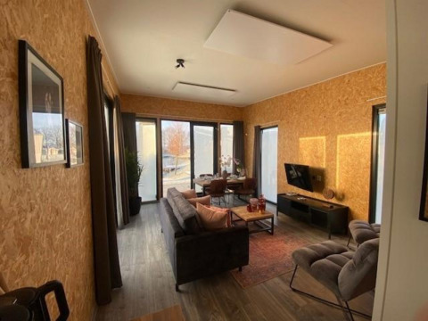 Moderne lodge woonkamer met grote ramen, houten wanden en gezellige inrichting op de IJssel Islands.