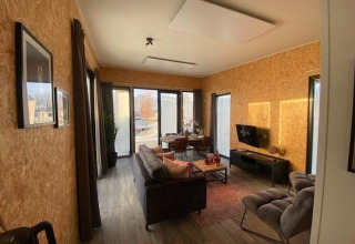 Salón moderno de lodge con grandes ventanas y paredes de madera en The IJssel Islands, Países Bajos.