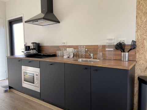 Moderne kitchenette bij Just Nature Light op de IJssel Islands, Nederland, met houtlook blad en zwarte kasten.