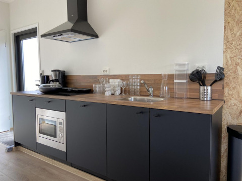Moderne kitchenette bij Just Nature Light op de IJssel Islands, Nederland, met houtlook blad en zwarte kasten.