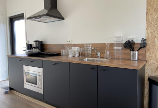 Moderne kitchenette bij Just Nature Light op de IJssel Islands, Nederland, met houtlook blad en zwarte kasten.