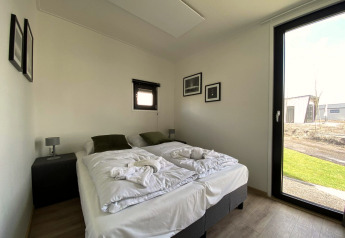 Lichte moderne slaapkamer in Just Nature Light lodge op de IJssel Islands, Nederland, met tweepersoonsbed.