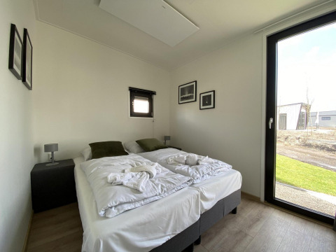 Lichte moderne slaapkamer in Just Nature Light lodge op de IJssel Islands, Nederland, met tweepersoonsbed.