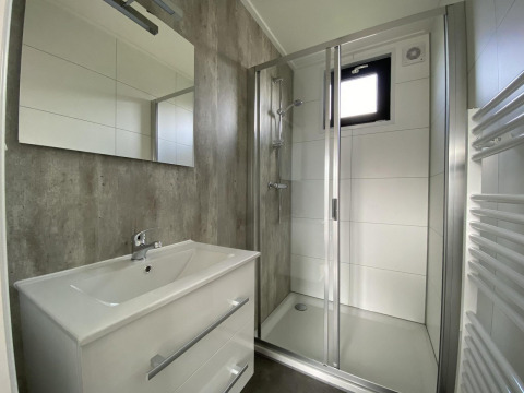 Modernes Badezimmer in der Just Nature Light Lodge mit Dusche, Waschbecken und Spiegel, IJssel Islands, Niederlande.