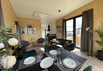 Moderne lodge Just Nature Light ved IJssel-øerne i Holland med åbent opholdsområde og spisebord.