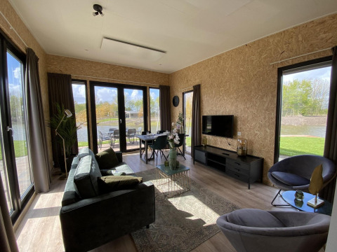Modernes Wohnzimmer in der Just Nature Light Lodge, IJssel Islands, Niederlande, mit großen Fenstern und Aussicht.