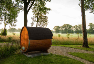 Fassförmige Holzhütte im grünen Park von Hofparken Wiltershaar, Gelderland, Niederlande, am Morgen.