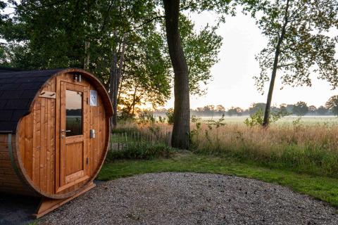 Sauna de madera en forma de barril al amanecer en Hofparken Wiltershaar, Gelderland, Países Bajos.