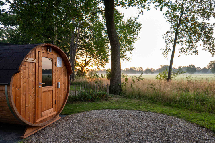 Træsauna i tøndeform ved solopgang i et naturområde i Hofparken Wiltershaar, Gelderland, Holland.