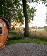 Fassförmige Holzsauna bei Sonnenaufgang im Naturbereich von Hofparken Wiltershaar, Gelderland.