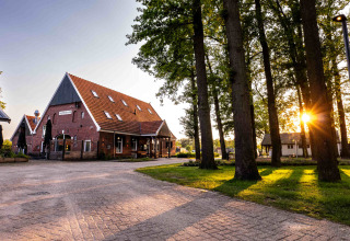 Sonnenaufgang im Ferienpark Hofparken Wiltershaar in Gelderland, Niederlande, mit Bäumen und roten Ziegelhäusern.