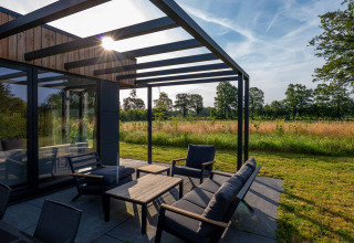 Moderne terras met pergola en tuinmeubilair, zon licht over weide, Hofparken Wiltershaar, Gelderland, Nederland.