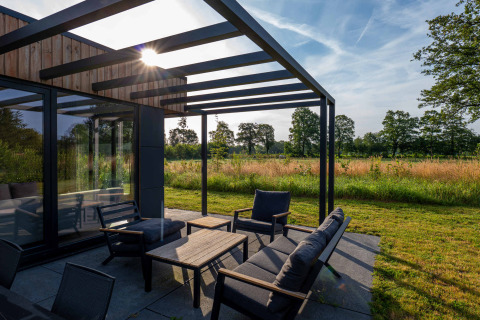 Moderne terras met pergola en tuinmeubilair, zon licht over weide, Hofparken Wiltershaar, Gelderland, Nederland.