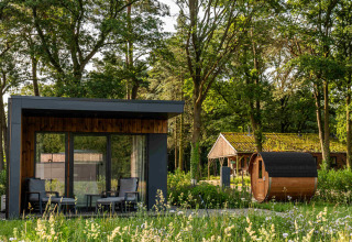Moderne hytte og tøndesauna blandt træer på Hofparken Wiltershaar feriepark i Gelderland, Holland.