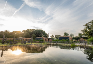 Udsigt over feriehytter, saunaer og en naturlig svømmesø ved Hofparken Wiltershaar i Gelderland, Holland.