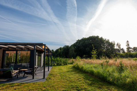 Moderne vakantiewoning in Hofparken Wiltershaar, omgeven door groene velden en bomen te Gelderland, Nederland.