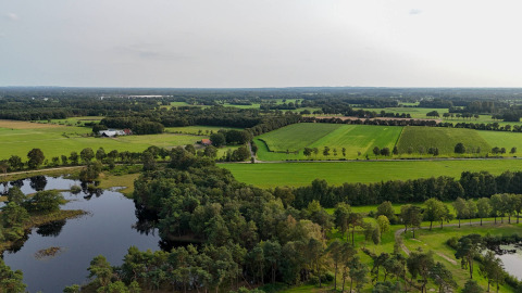 Vista aérea de campos verdes, bosque y un lago en Hofparken De Bergvennen, un parque vacacional en Overijssel, Países Bajos.