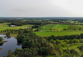 Vista aerea di campi verdi, foresta e un lago presso Hofparken De Bergvennen, parco vacanze a Overijssel, Paesi Bassi.