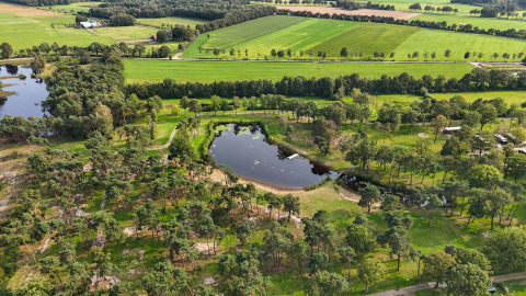 Vista aérea de Hofparken De Bergvennen, parque vacacional con lago y campos verdes en Overijssel, Países Bajos.