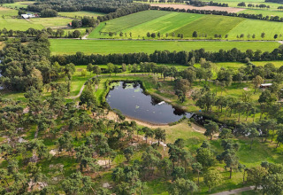 Vista aérea de Hofparken De Bergvennen, parque vacacional con lago y campos verdes en Overijssel, Países Bajos.