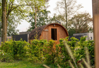 Træhytte omgivet af grønne buske i Hofparken De Bergvennen feriepark, Overijssel, Holland, om sommeren.