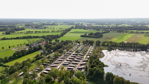 Luchtfoto van vakantiepark Hofparken De Bergvennen tussen velden en een vijver in Overijssel, Nederland.
