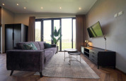 Stijlvolle woonkamer in Just Nature lodge op de IJssel Eilanden, Nederland, met zetel, tv en grote ramen.