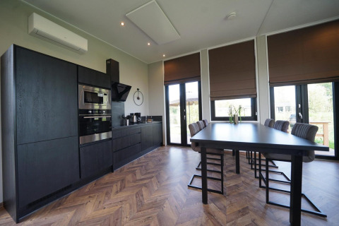 Modern black kitchen and dining area in Just Nature lodge at The IJssel Islands, Netherlands.