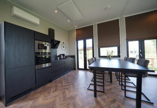 Modern black kitchen and dining area in Just Nature lodge at The IJssel Islands, Netherlands.