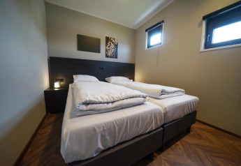 Chambre moderne au lodge Just Nature aux îles IJssel, Pays-Bas, avec deux lits simples et fenêtres.