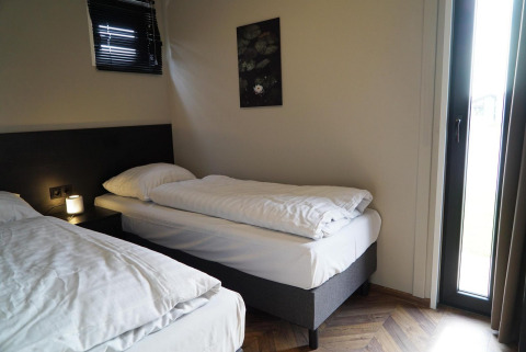 Værelse med to enkeltsenge, moderne indretning, vindue og kunstværk på væggen på Just Nature lodge.