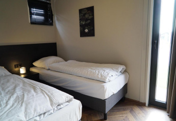 Værelse med to enkeltsenge, moderne indretning, vindue og kunstværk på væggen på Just Nature lodge.