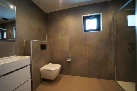 Baño moderno con inodoro suspendido, lavabo, ducha y ventana en Just Nature, IJssel Islands, Países Bajos.
