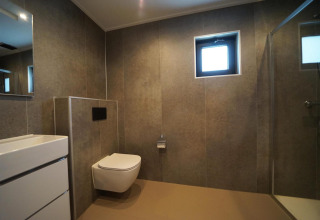 Baño moderno con inodoro suspendido, lavabo, ducha y ventana en Just Nature, IJssel Islands, Países Bajos.