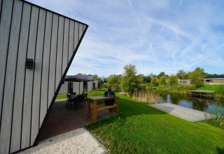 Moderna lodge Just Nature alle IJssel Islands nei Paesi Bassi con terrazza, lago e vegetazione verde.
