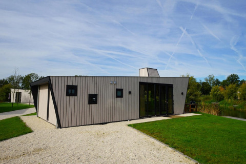 Moderno lodge Just Nature con pannelli in legno chiaro alle IJssel Islands, Paesi Bassi, circondato dal verde.