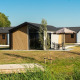 Udendørs foto af Velthorst lodge med moderne feriehytter, grønne græsplæner og haveborde under parasoller.