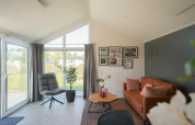 Salon du lodge Velthorst aux Îles IJssel, Pays-Bas, avec grandes fenêtres et canapé marron moderne.