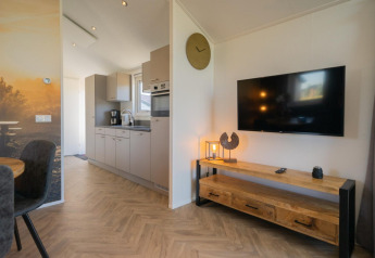 Moderne lodge-stue og køkken på Velthorst ved IJssel-øerne i Holland med træmøbler og fladskærmstv.
