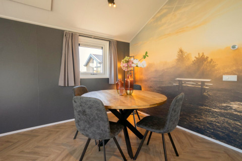 Eethoek met ronde tafel, vier stoelen en natuurmuurschildering in Velthorst lodge op de IJssel Eilanden, Nederland.