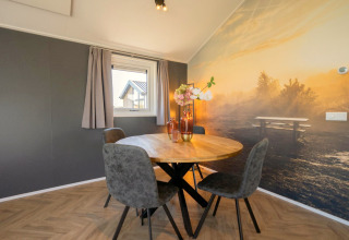 Eethoek met ronde tafel, vier stoelen en natuurmuurschildering in Velthorst lodge op de IJssel Eilanden, Nederland.