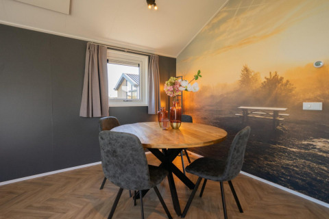 Essbereich mit rundem Tisch, vier Stühlen und Naturwandbild in der Velthorst-Lodge auf den IJsselinseln, Niederlande.