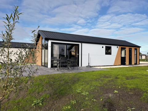 Moderne Velthorst-lodge bij The IJssel Islands in Nederland met terras, tuinmeubilair en groene grasmat.