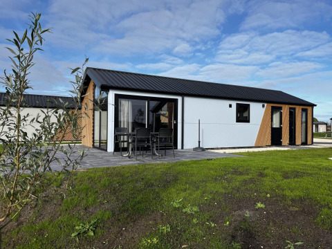 Moderne Velthorst-Lodge bei The IJssel Islands in den Niederlanden, Terrasse mit Gartenmöbeln und Rasen.